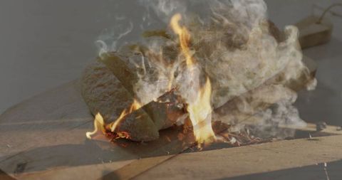 Flaming wooden plank on workshop floor with vibrant smoke