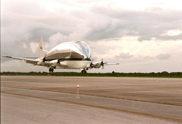NASA's Super Guppy airplane is captured landing at Kennedy Space Center with the ISS S1 truss segment aboard. This image can be used in articles and presentations about space missions, NASA, aerospace engineering, and specialized aircraft. Suitable for educational and documentary projects focused on the International Space Station and logistics involved in space exploration.