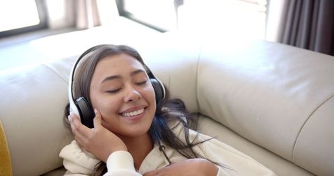 Smiling Woman Relaxing on Couch Enjoying Music with Headphones