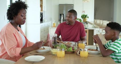 African american family sharing sunny breakfast at modern kitchen table, minimalist home