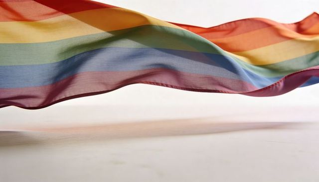 Flowing translucent rainbow scarf rippling across minimal studio backdrop with soft shadow