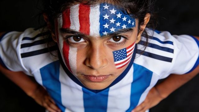 Determined preteen soccer fan wearing american flag face paint and blue-white jersey