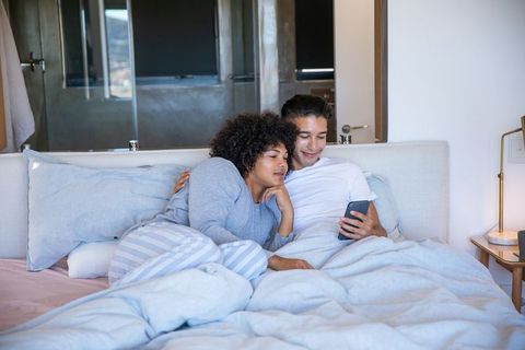 Couple Relaxing in Bed Sharing a Smartphone
