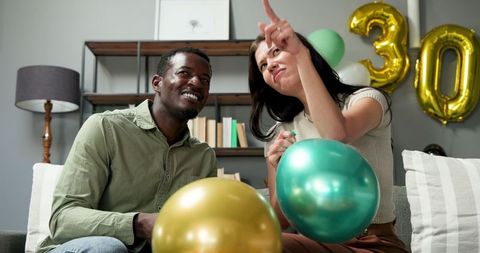 Multiracial Couple Preparing Birthday Party with Balloons at Home