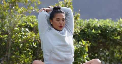 Mid-Adult Woman Stretching Outdoors in a Garden Setting, Promoting Wellness