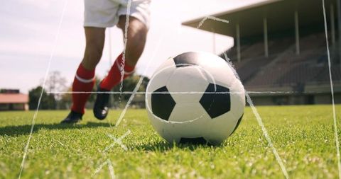Football Player Kicking Soccer Ball on Grass Field