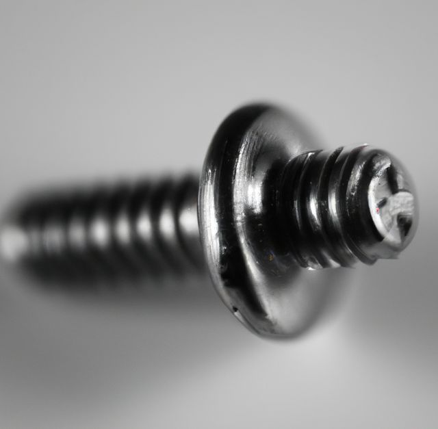 Detailed macro view of a metal screw focusing on the threaded shaft and Phillips head with a blurred backdrop. Ideal for use in articles or advertisements related to hardware, construction, DIY projects, and fastening solutions. Can be featured in technical manuals, educational materials, or promotional content for tools and repair kits.
