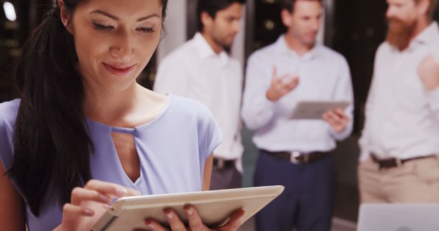 Businesswoman Using Tablet in Office with Colleagues in Background - Download Free Stock Images Pikwizard.com