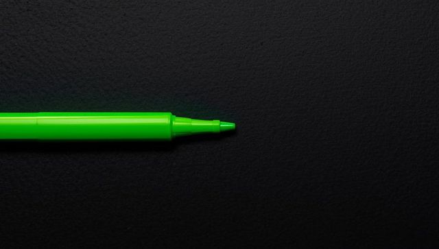Vibrant green marker pen on dark surface for creative design