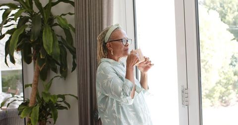 Senior African American Woman Relaxing by Sunny Window with Drink