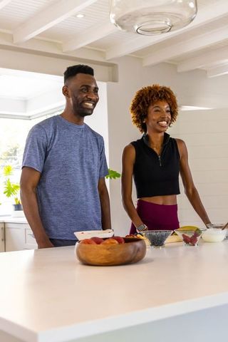 Smiling african american couple preparing breakfast in bright modern farmhouse kitchen