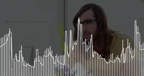 Man wearing glasses analyzing data visualization overlay with bar and line charts at desk