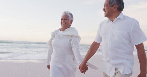 Senior Couple Walking on Beach Hand in Hand at Sunset