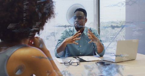 Man gesturing while explaining strategy during collaborative office meeting with laptop