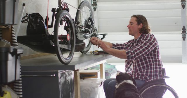 Focused caucasian disabled man in wheelchair repairing bike in garage. domestic lifestyle with physical disability.