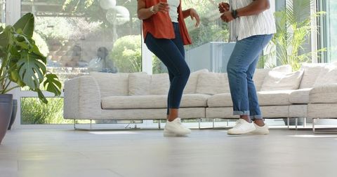 African american couple dancing in bright modern living room wearing denim and sneakers
