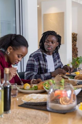African American couple enjoying cozy home dinner at wooden table in sunlit modern dining room