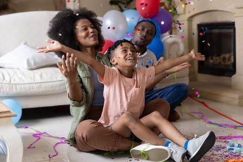 African american family celebrating at home with smiling child and colorful confetti
