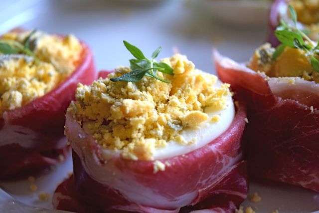 Close-up of deviled eggs topped with crumbled yolk and fresh herb garnish. Ideal for illustrating gourmet culinary dishes, festive celebration recipes, and elegant food presentations.