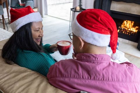 Cozy holiday moment: couple enjoying warm beverages by fireplace