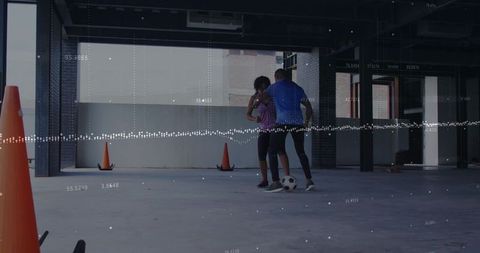 Practicing soccer dribbling in urban parking garage with cones and digital data overlay