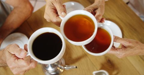 Friends toasting with tea and coffee during social gathering