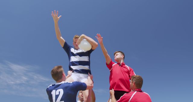 Opposing caucasian male rugby teams lifting players on sunny pitch during game, copy space. Teamwork, match, game, sport, team sport and competition, unaltered.