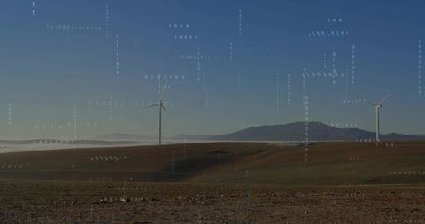 Wind turbines generating clean energy across foggy valley with digital binary overlay