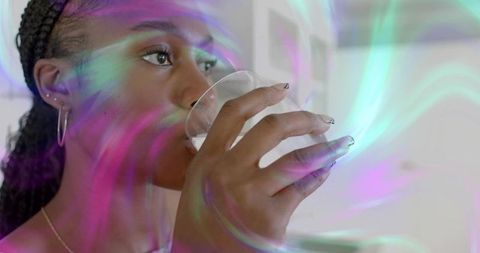 Woman in modern kitchen sipping drink among vibrant swirls