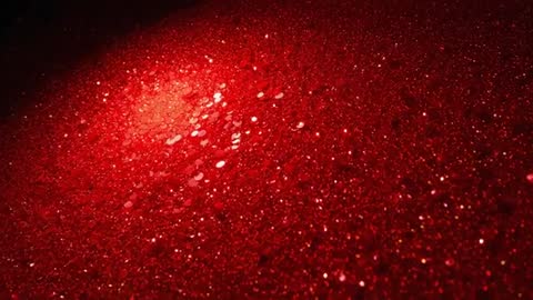 Shimmering red sequin surface catching shifting spotlight in slow-motion macro
