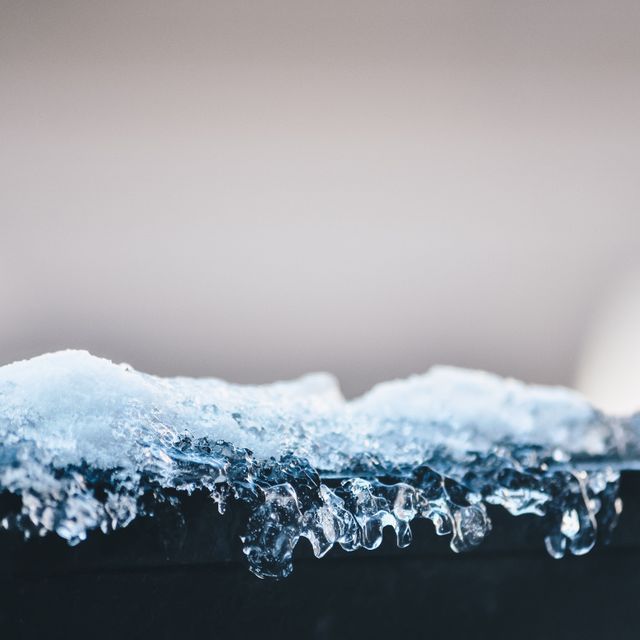 Detailed close-up photo of melting ice on a surface displaying intricate ice crystals and water droplets. Ideal for use in winter, nature and climate change projects as well as backgrounds for websites, advertisements, and educational materials.