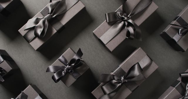 Overhead view of black gift boxes tied with black ribbons on black background. Luxury treat, present, shopping, black friday sale and retail concept digitally generated image.