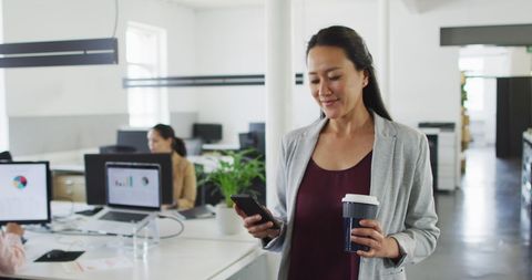 Smiling Businesswoman with Coffee Using Smartphone in Modern Office - Download Free Stock Images Pikwizard.com