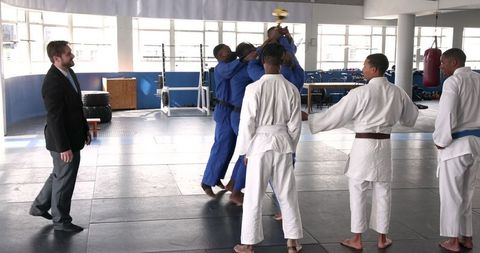 Diverse judo team celebrating victory with gold trophy in dojo