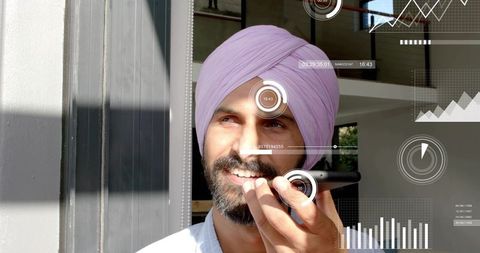 Smiling indian man in pink turban speaking into phone with futuristic hud overlays