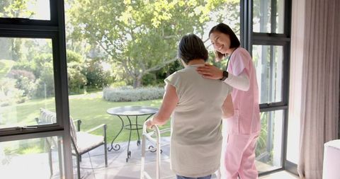Caring Asian Caregiver Assisting Elderly Woman Indoors