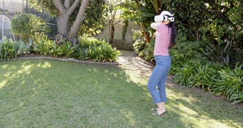 Woman Experiencing VR Technology in Green Garden Setting