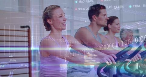 Group indoor cycling class pedaling on stationary bikes with digital fitness data overlay