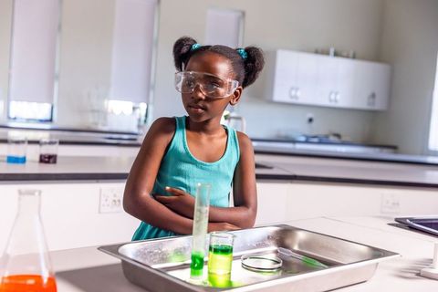 Young african american girl conducting colorful chemistry experiment in school lab
