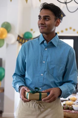 Young man smiling holding gift at festive gathering