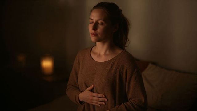 Woman practicing mindful breathing by candlelight for nighttime calm and sleep preparation