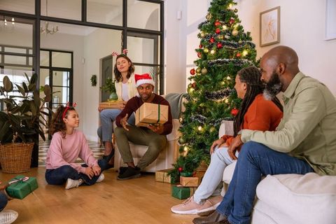 Diverse family exchanging gifts near christmas tree in cozy living room