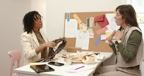 Designers reviewing striped scarf and fabric swatches in collaborative fashion meeting