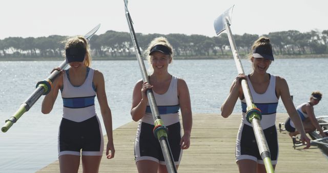 Female Rowers Carrying Oars on Sunny Lakeside Dock - Download Free Stock Images Pikwizard.com