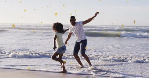 Joyful Father and Daughter Playing in Ocean Waves with Golden Stars