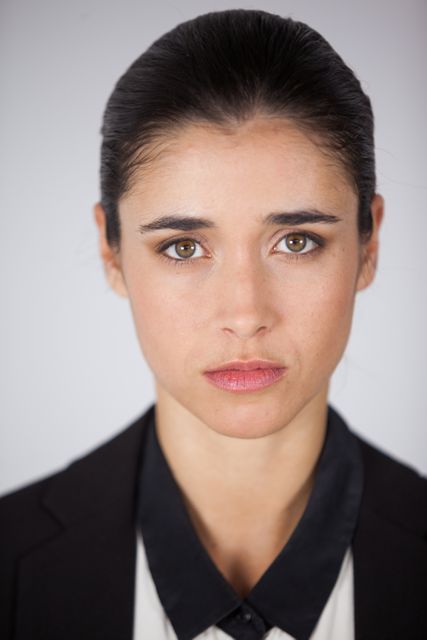 This image features a close-up portrait of a serious woman wearing a contact lens, dressed in business attire against a white background. Ideal for use in professional and corporate contexts, such as business presentations, websites, and promotional materials. It conveys confidence, focus, and professionalism.