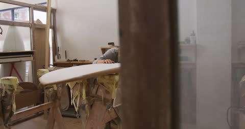 Surfboard Maker Preparing Board in Workshop