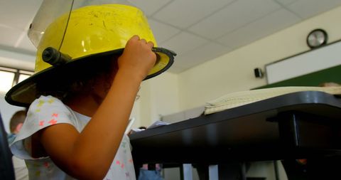 Schoolgirl wearing firefighter helmet in classroom demonstration