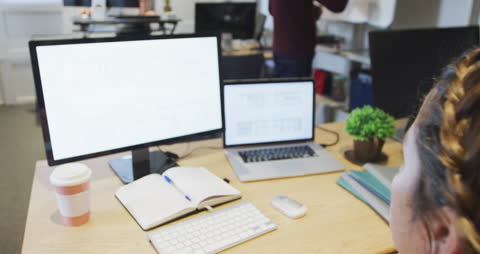 Businesswoman Analyzing Data on Dual Screens in Modern Office