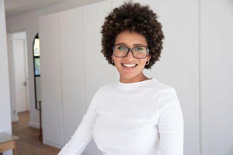 Confident woman smiling in modern home interior wearing eyeglasses